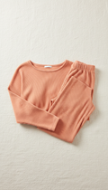 A perfectly centered product shot of a women's loungewear set in Soft Coral, featuring a top and pants combination. The...